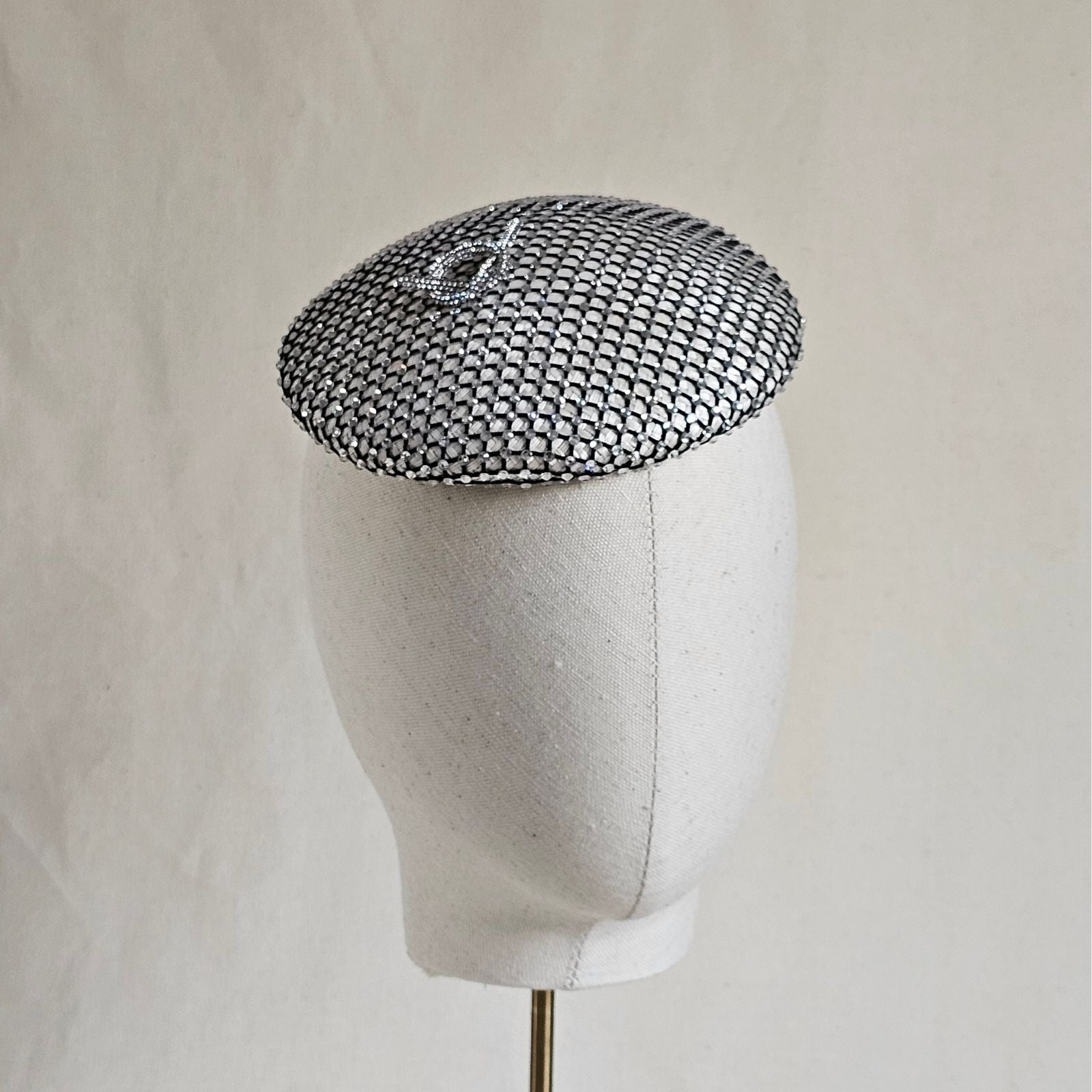 Ivory beret with intricate crystal mesh and elegant pretzel knot embellishment, angle view.