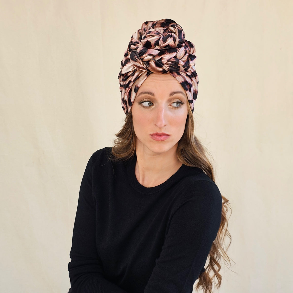 Leopard print velour braid rose turban, worn on a seated model.