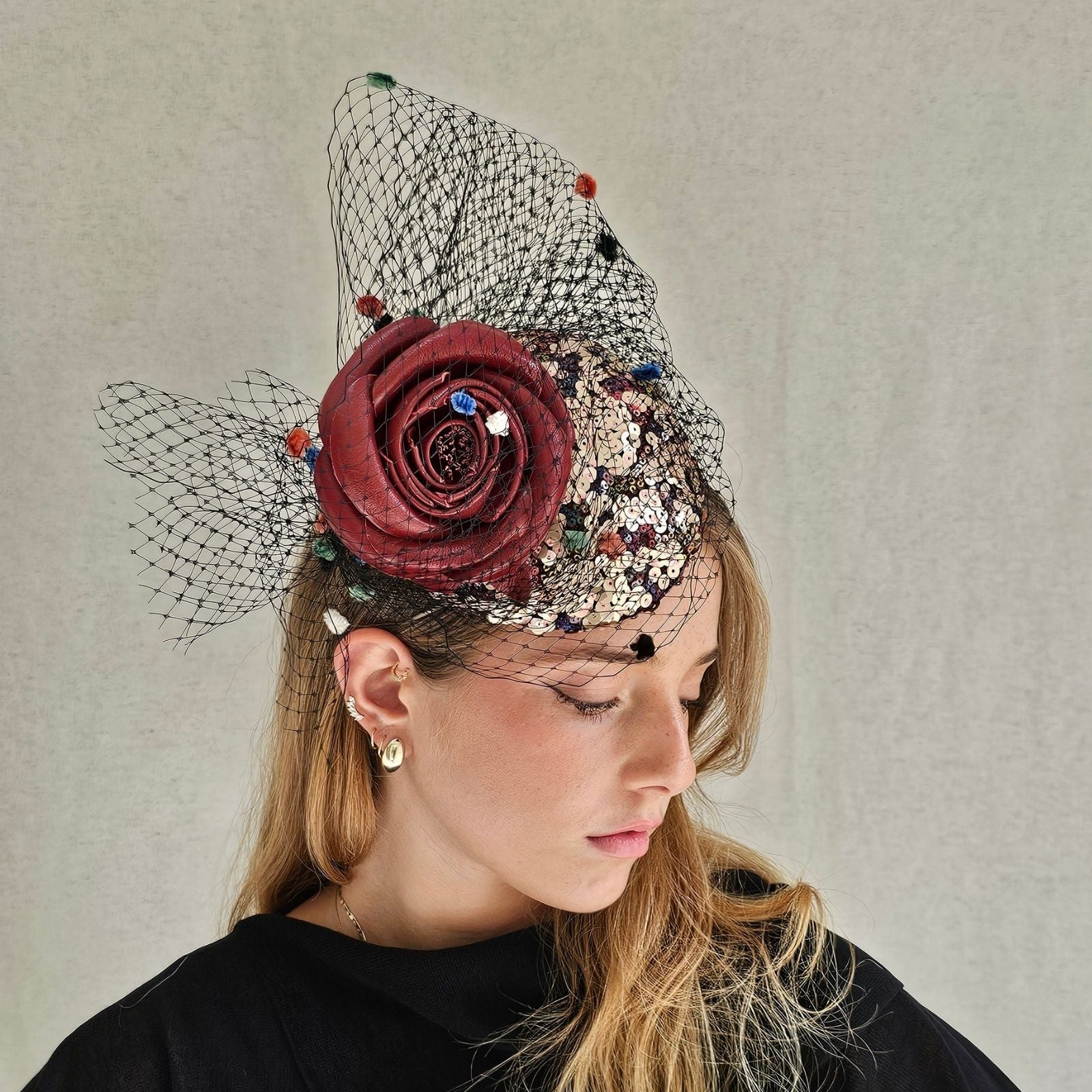 Multicolour sequin mini beret with red rose embellishment and dot veiling, angle view.