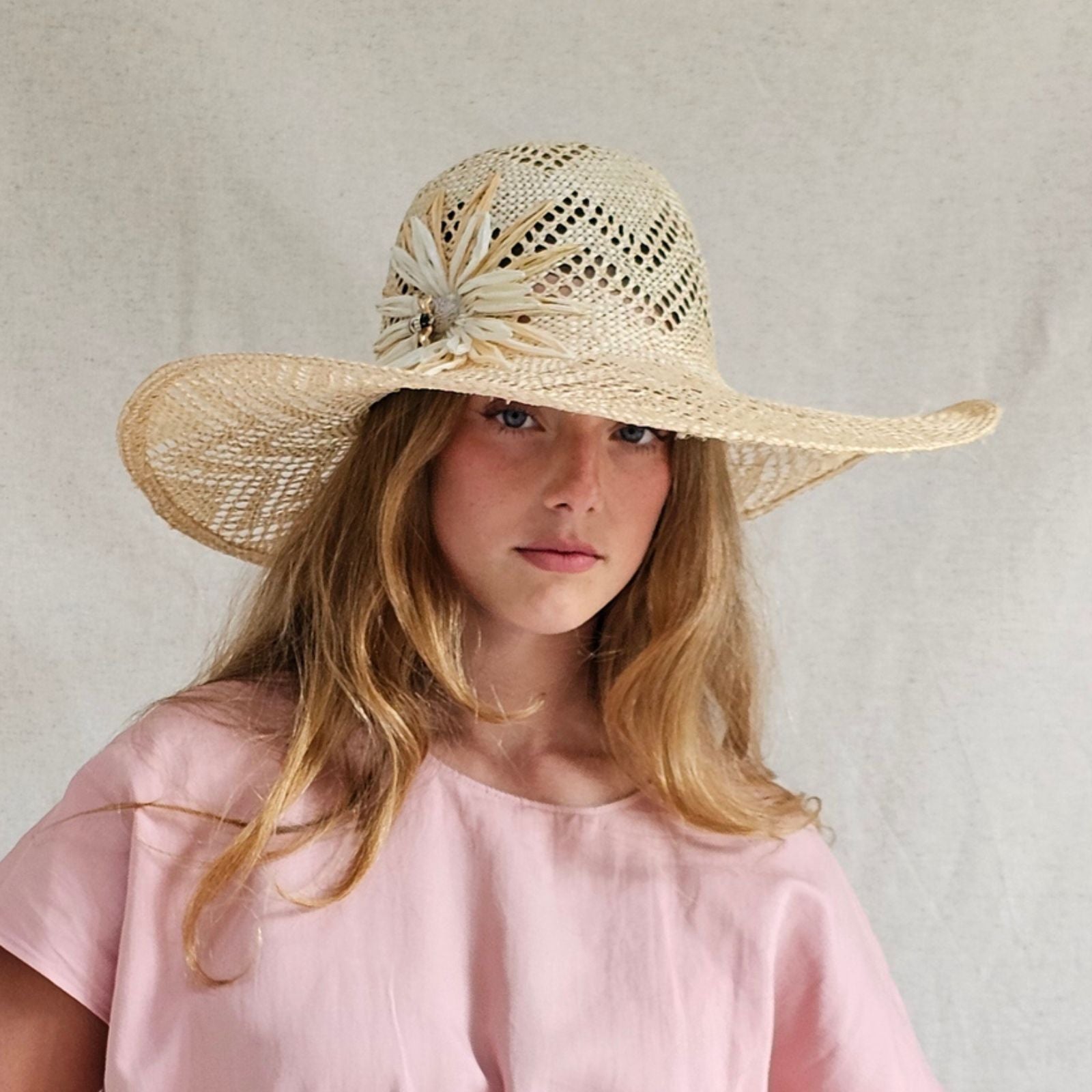 Natural mesh straw sunhat with beautiful flower embellishment, front view.