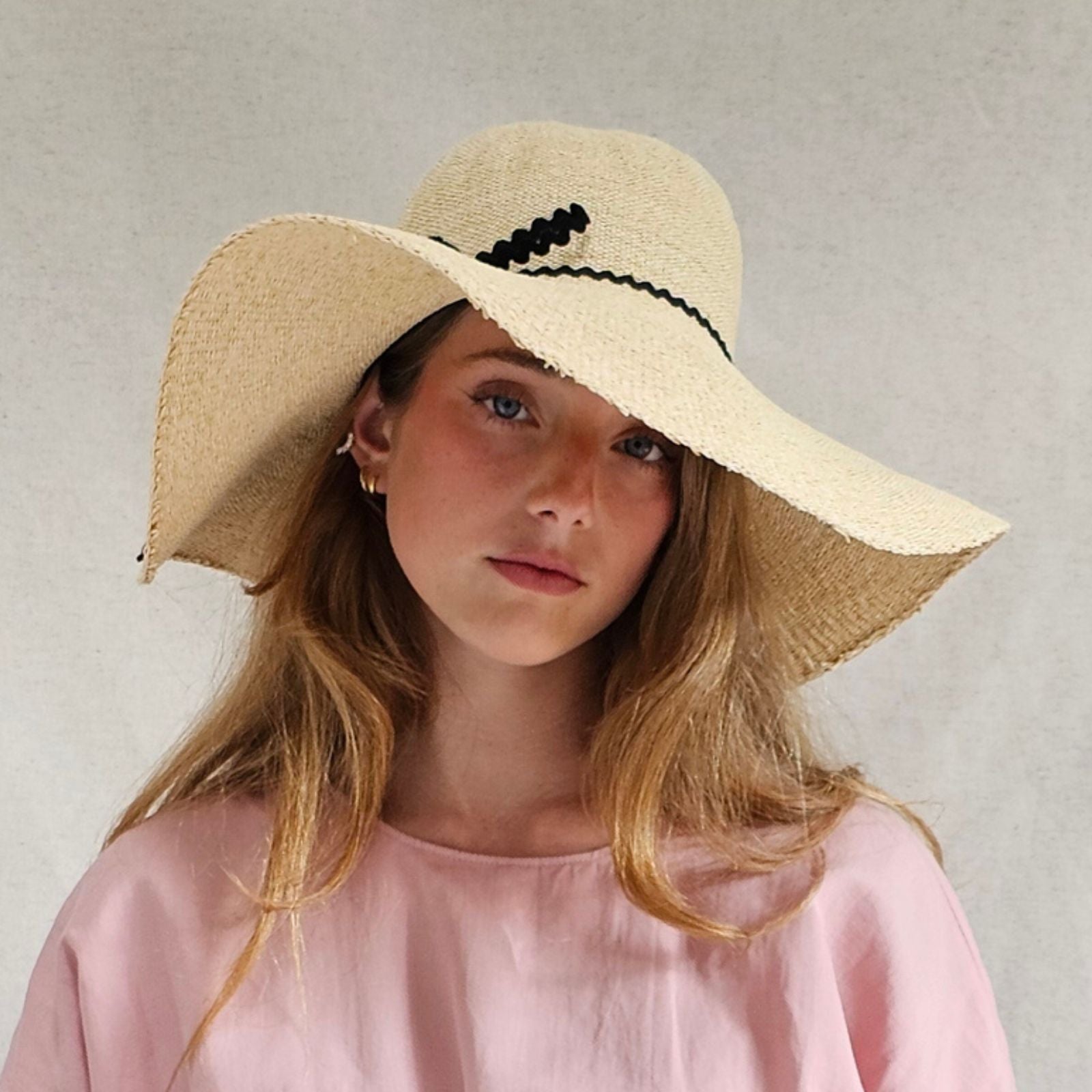 Natural straw sunhat with elegant black bow embellishment, front view.