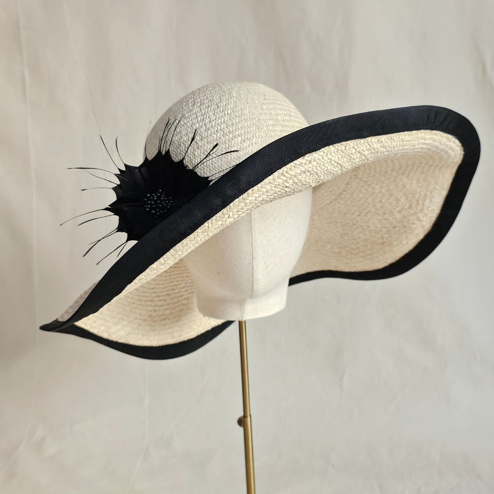 natural straw sunhat with beautiful black flower and rim, front view.