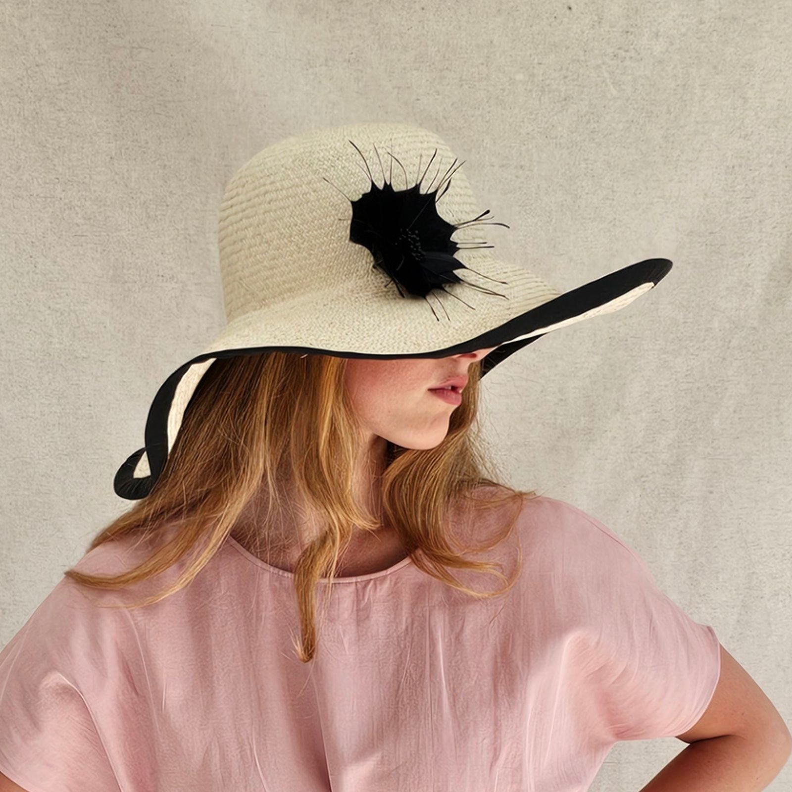 Natural straw sunhat with beautiful black flower and rim, side view.
