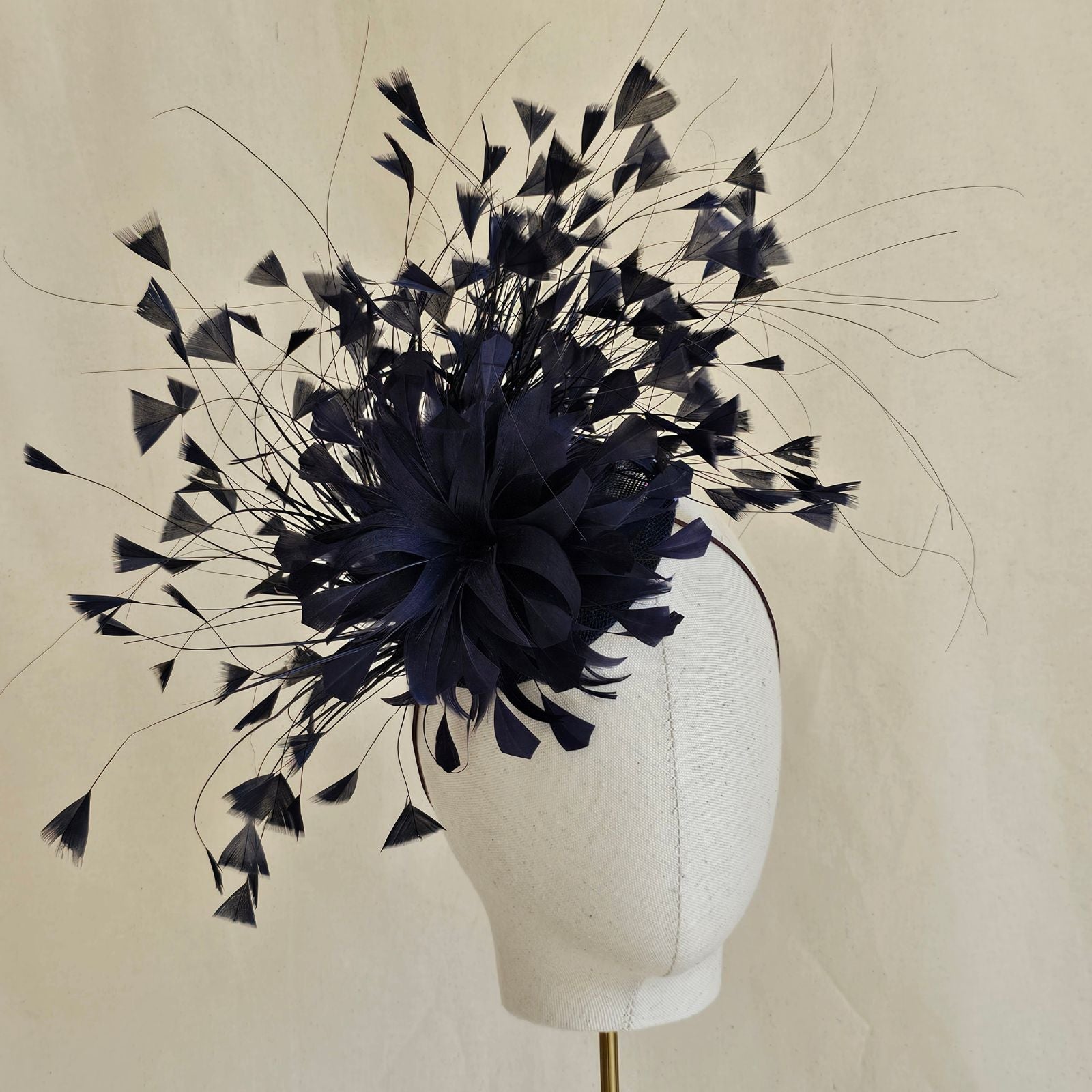 Navy feather fascinator with feather flower, front view.