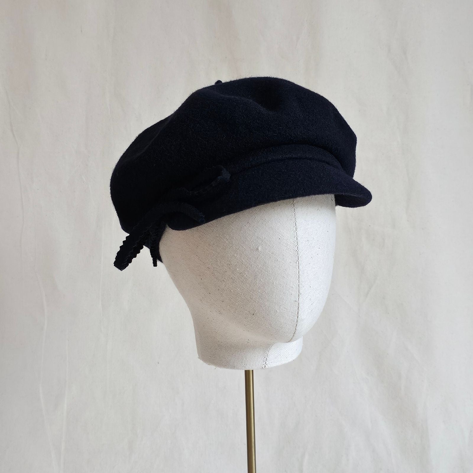 Navy wool cap with bow embellishment, angle view.
