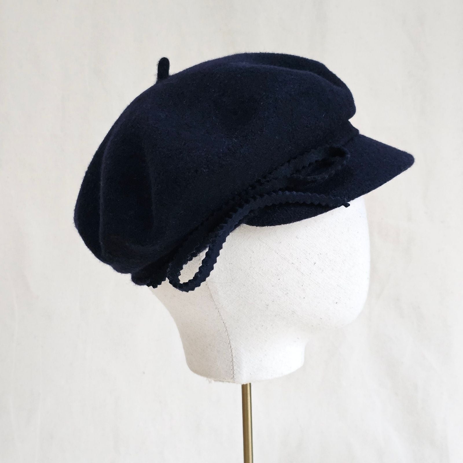 Navy wool cap with bow embellishment, side view.