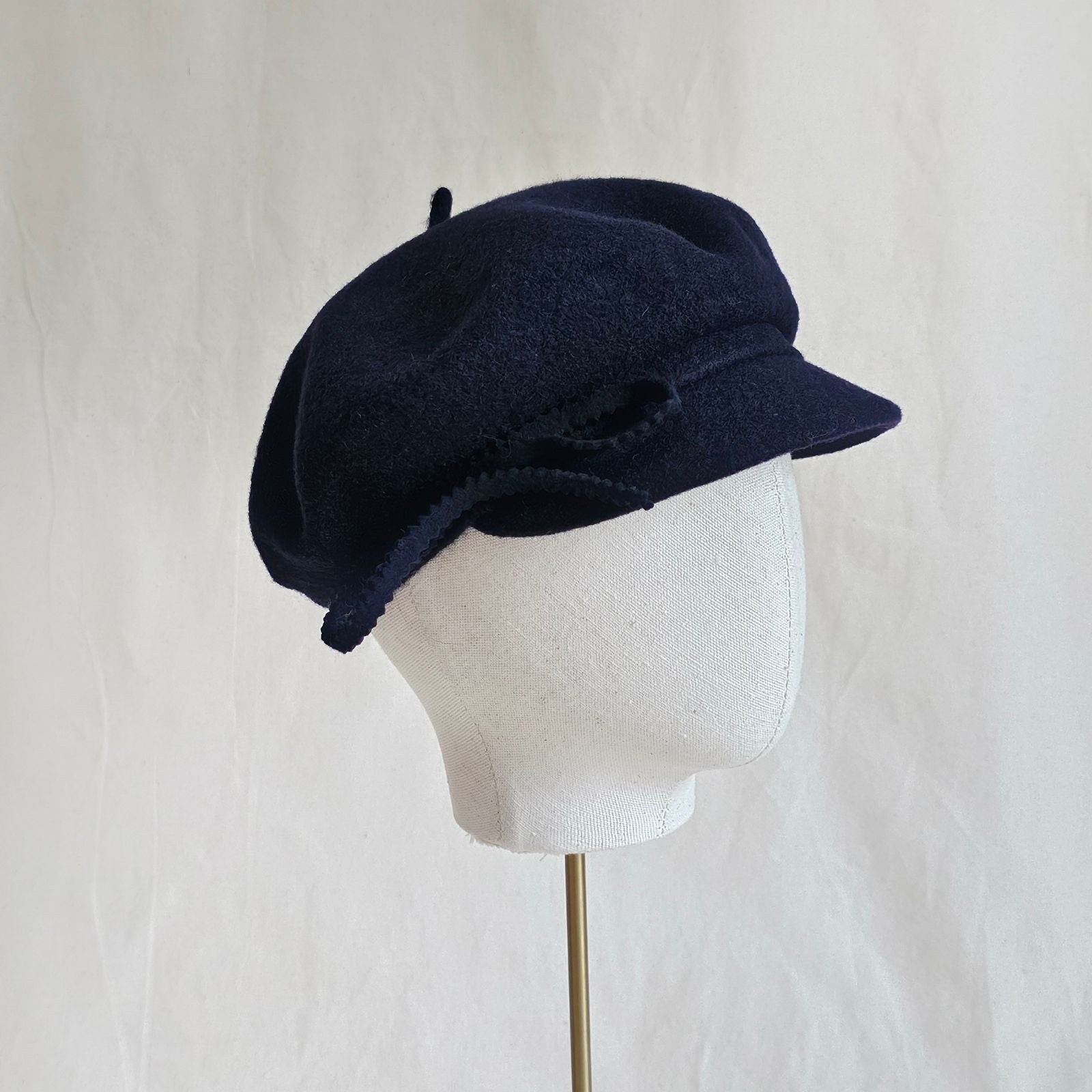 Navy wool cap with bow embellishment, side view.