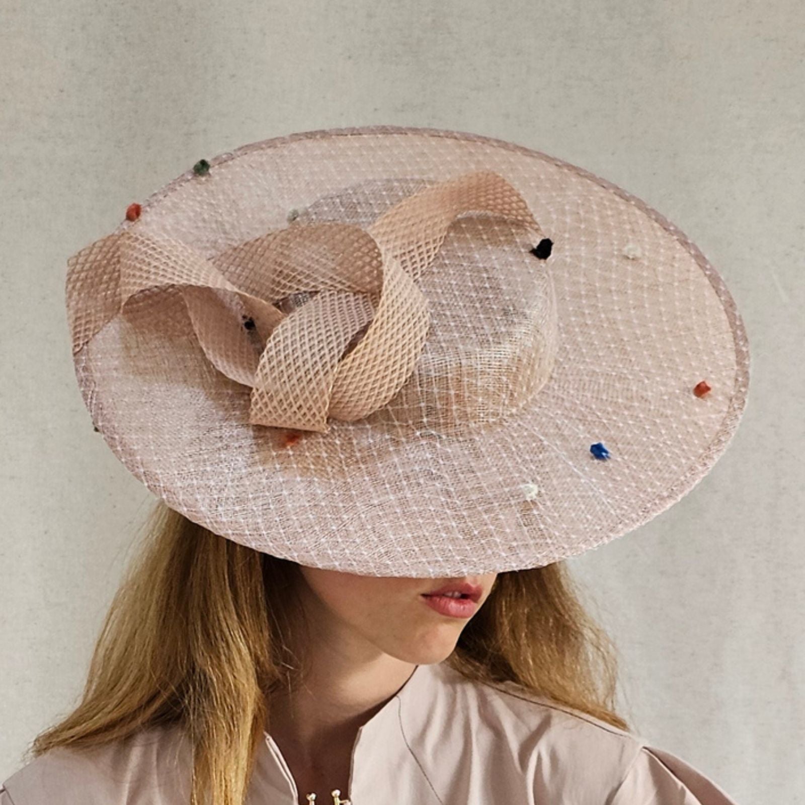 Nude sinamay boater hat with multicolour dot veil and elegant swirl embellishment, side view.