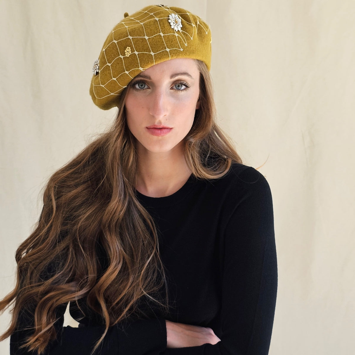 Ochre wool beret with white flowers and ivory veiling, worn on a
model.