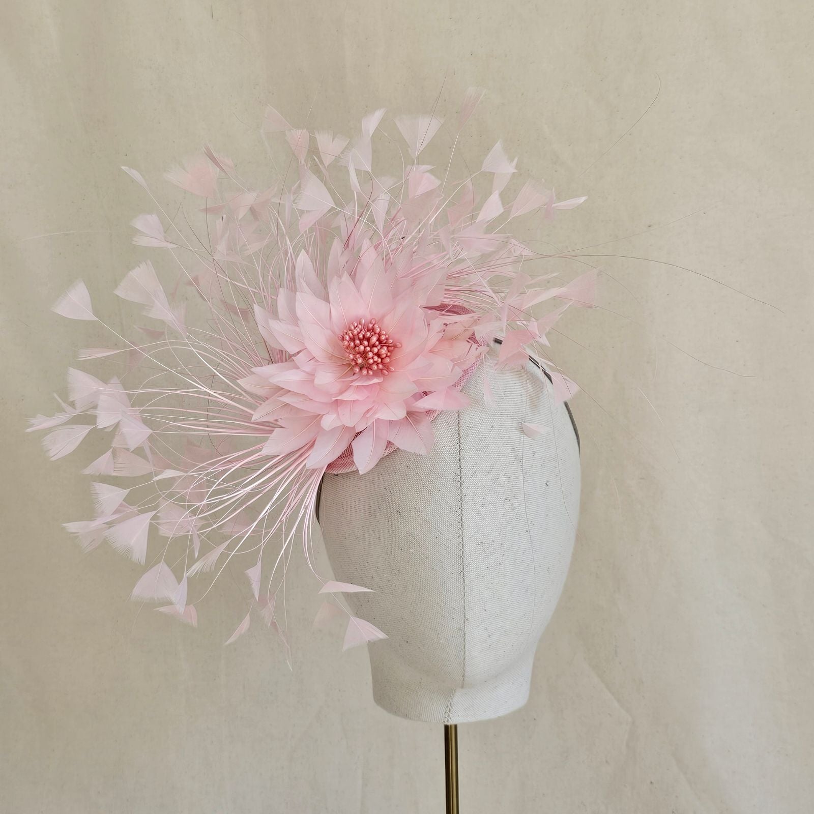Pink feather fascinator with feather flower, front view.