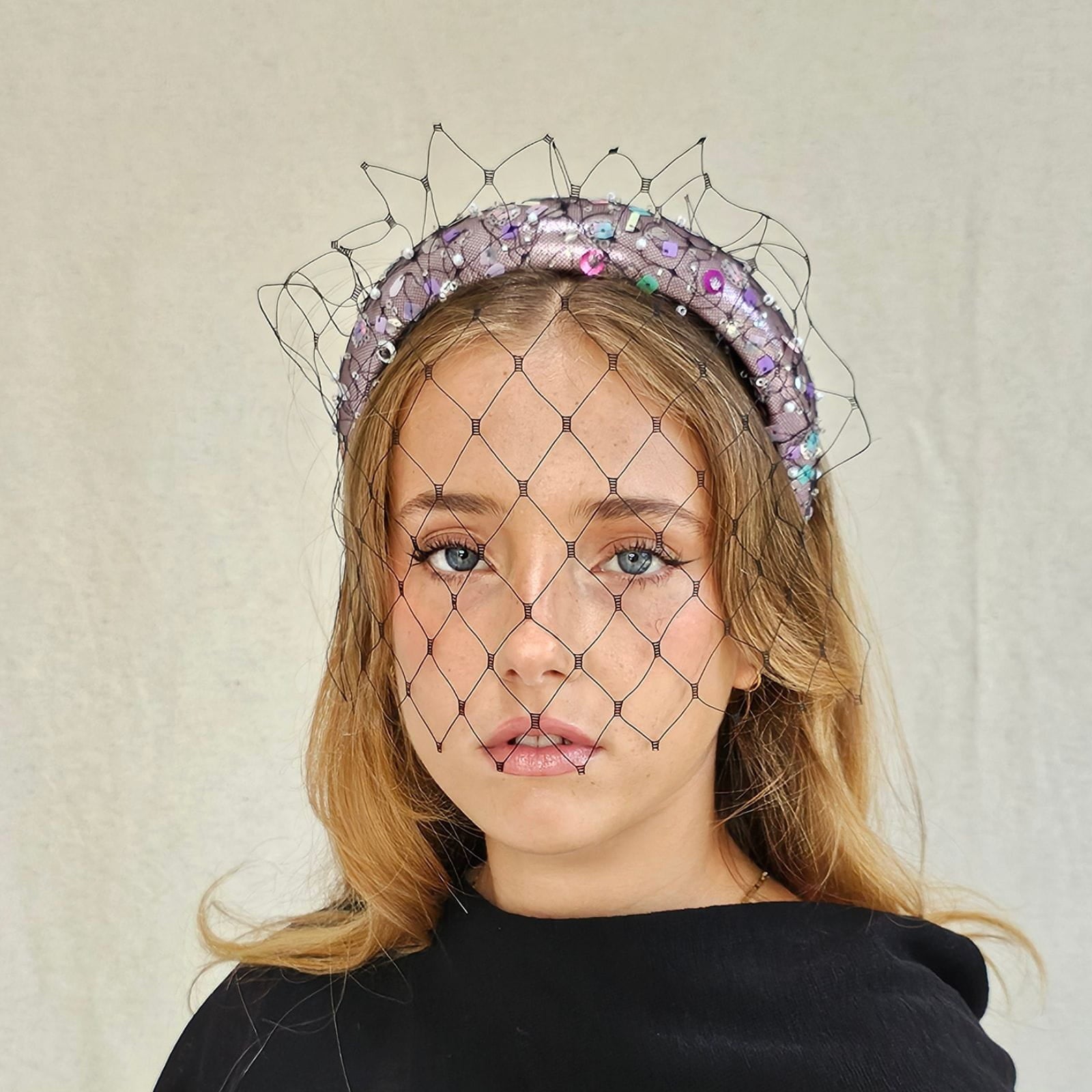 Pink lamé headband with multicolour sequins and black mesh veil, front view.
