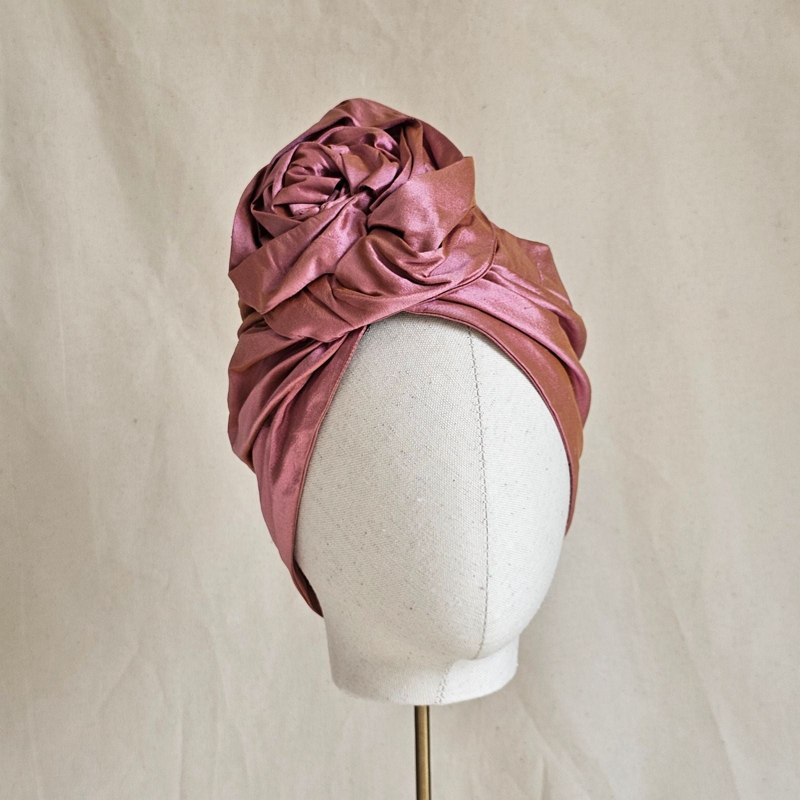 Pink silk turban with beautifully sculpted intricate rose knot, front view.