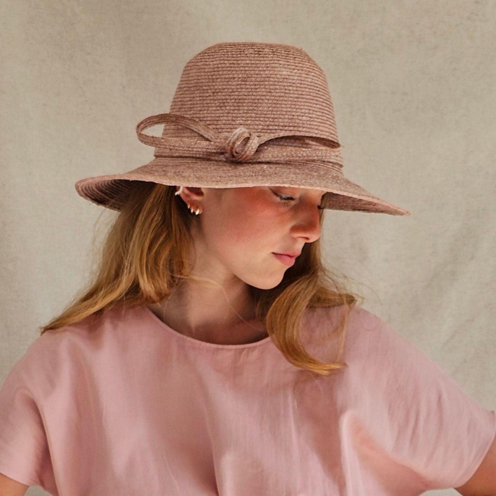 Pink straw sunhat with beautiful bow embellishment, side view.