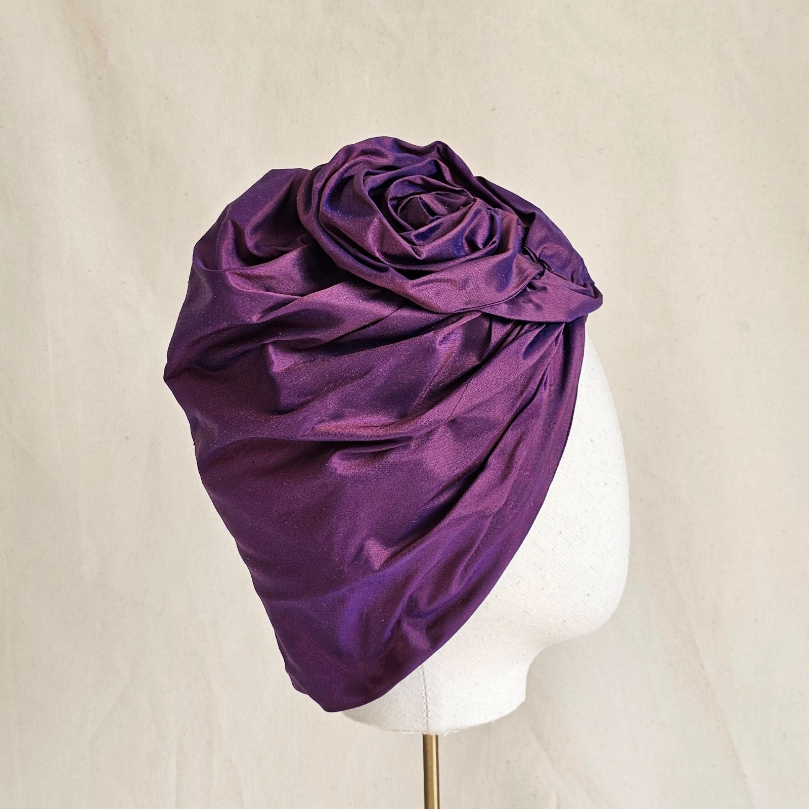 Purple silk turban with sculpted rose knot, side view.