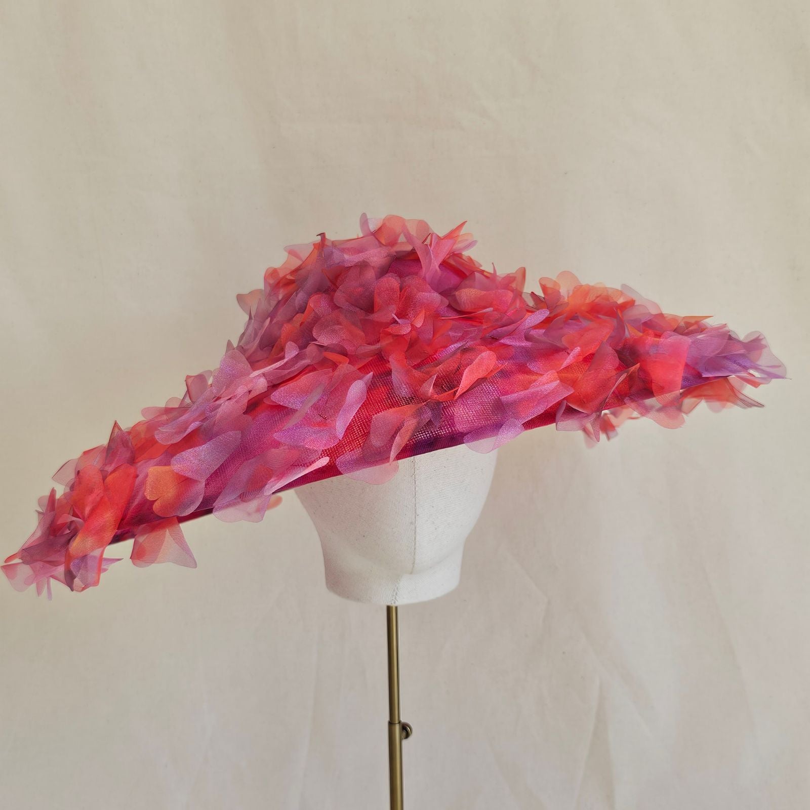 Red and pink shaded cut organza flower petals on a wide brim Ascot picture hat, front view.
