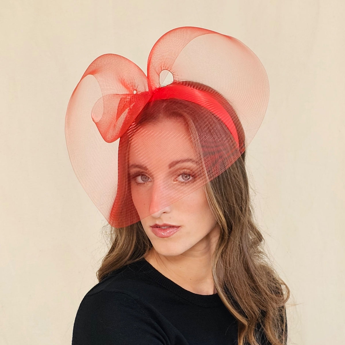 Red sculptural crin loop headpiece on headband with sheer curves framing the
face.