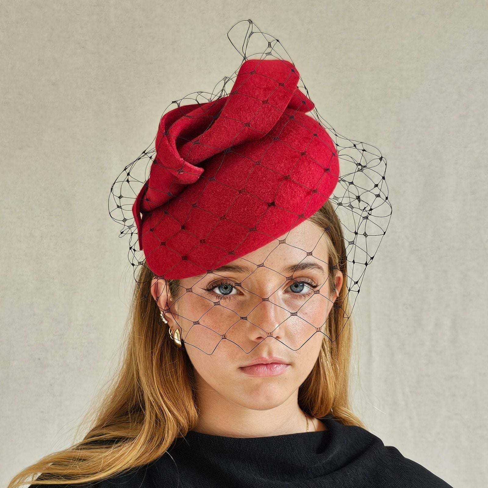 Red felt beret with dramatic twist and subtle black veil, front view.