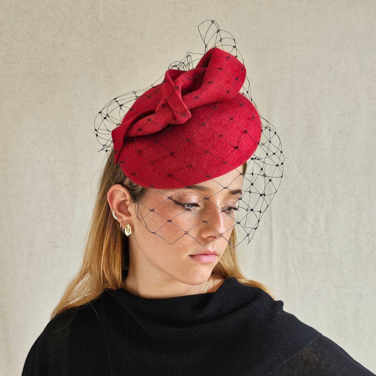 Red felt beret with dramatic twist and subtle black veil, side view.