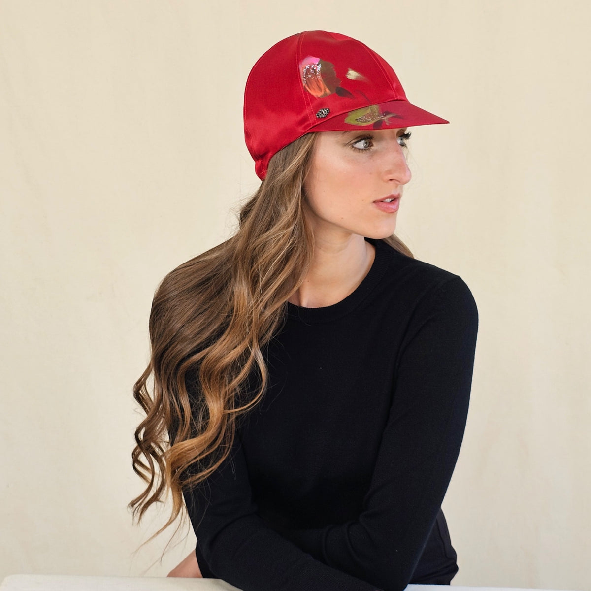 Side view of red hand-painted silk baseball cap on a seated model.