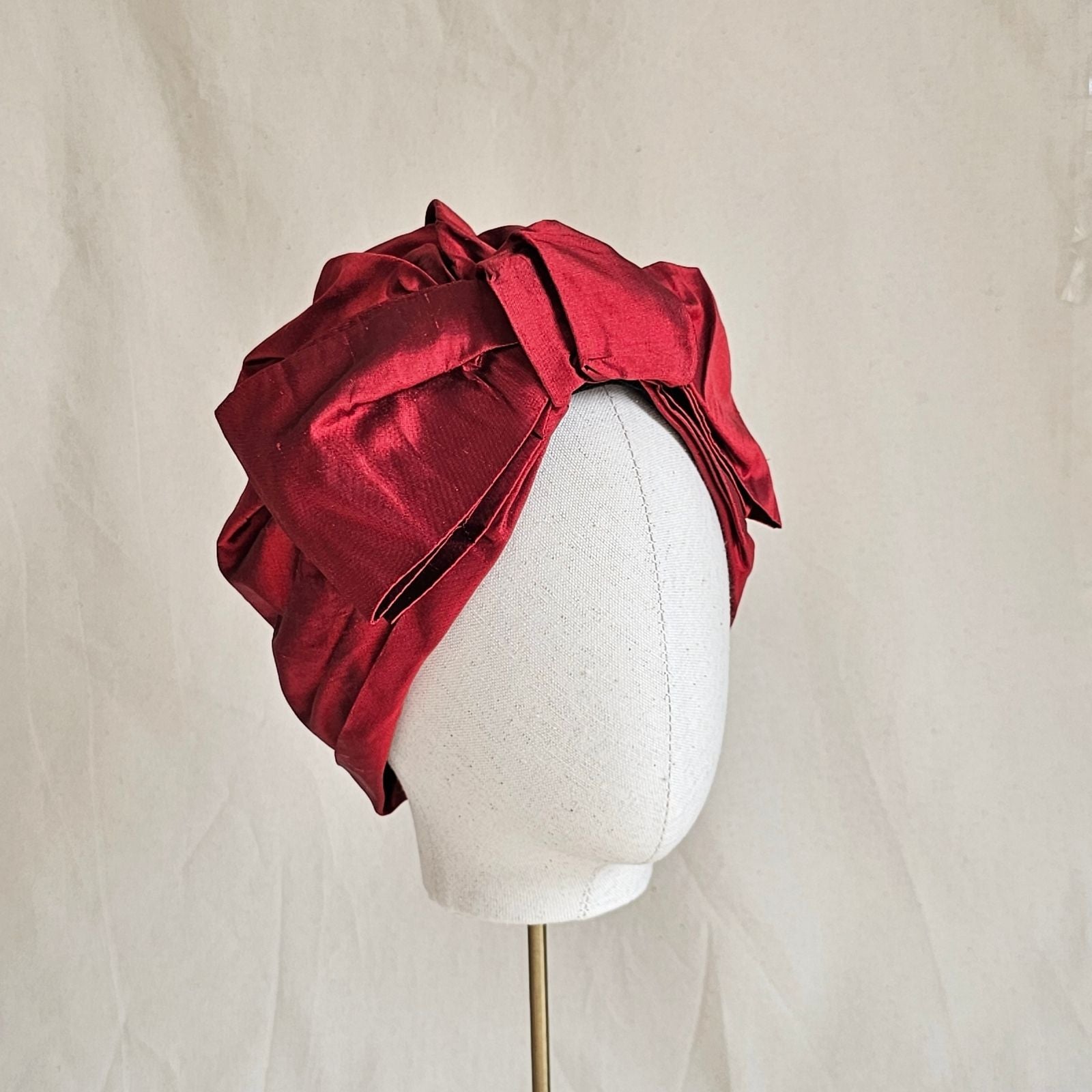 Red silk turban with bow embellishment, angle view.