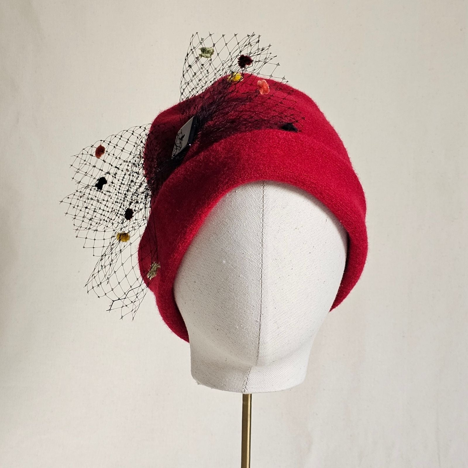 Red wool beanie with multicoloured spot veil bow, front view.