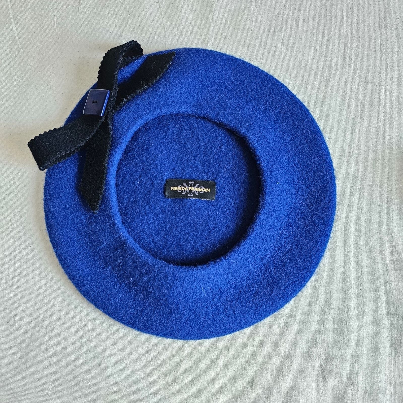Royal blue wool beret with black zig zag cut felt bow , underside.