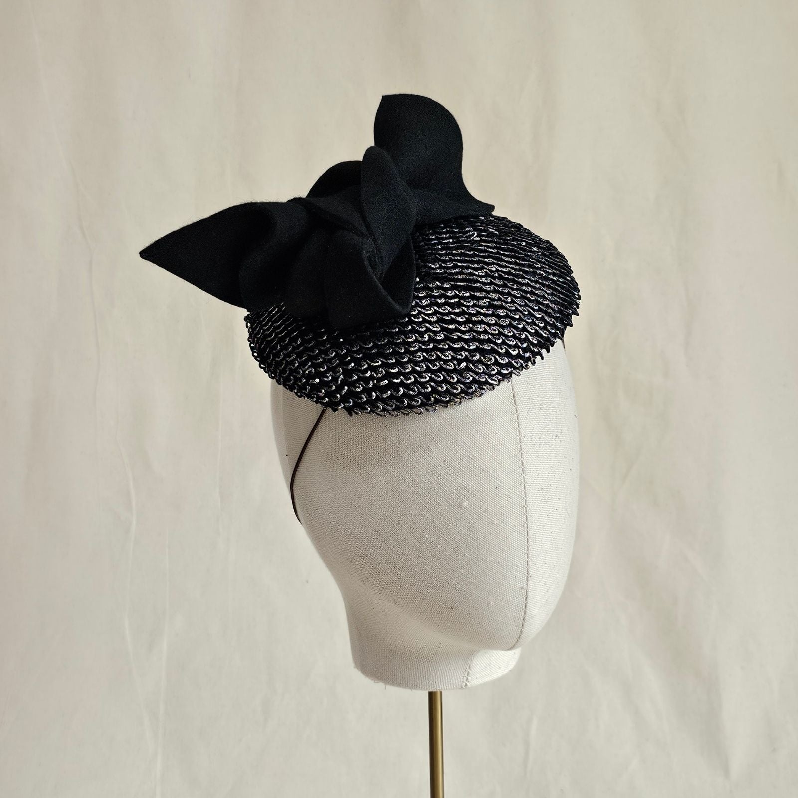 Silver black mini beret with black bow embellishment, angle view.