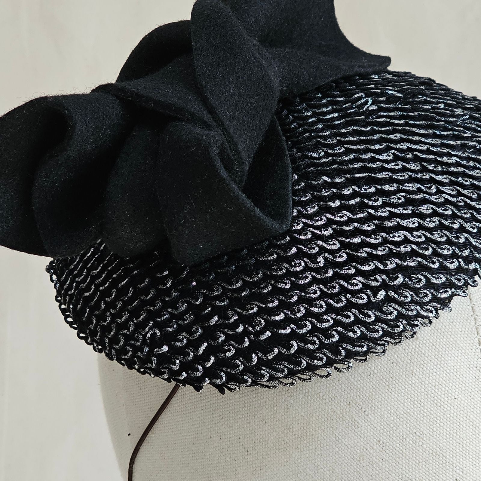 Detail of silver black mini beret with bow embellishment.