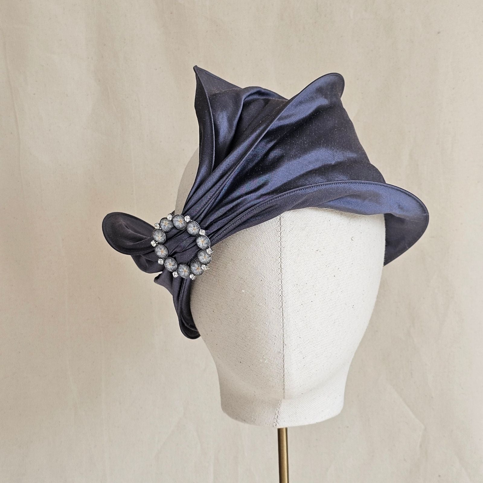Slate blue silk head wrap gathered into beautiful brooch, front view.