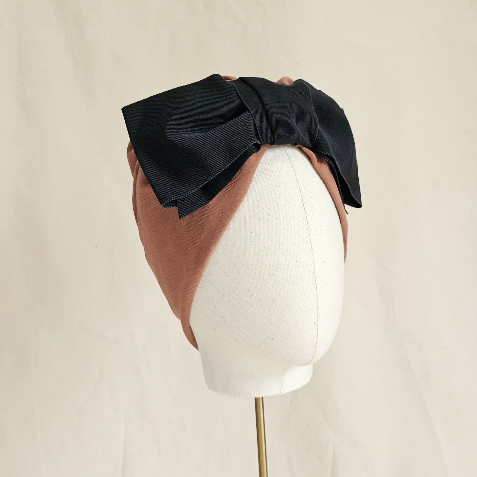 Tan cotton turban with dramatic black bow, angle view.
