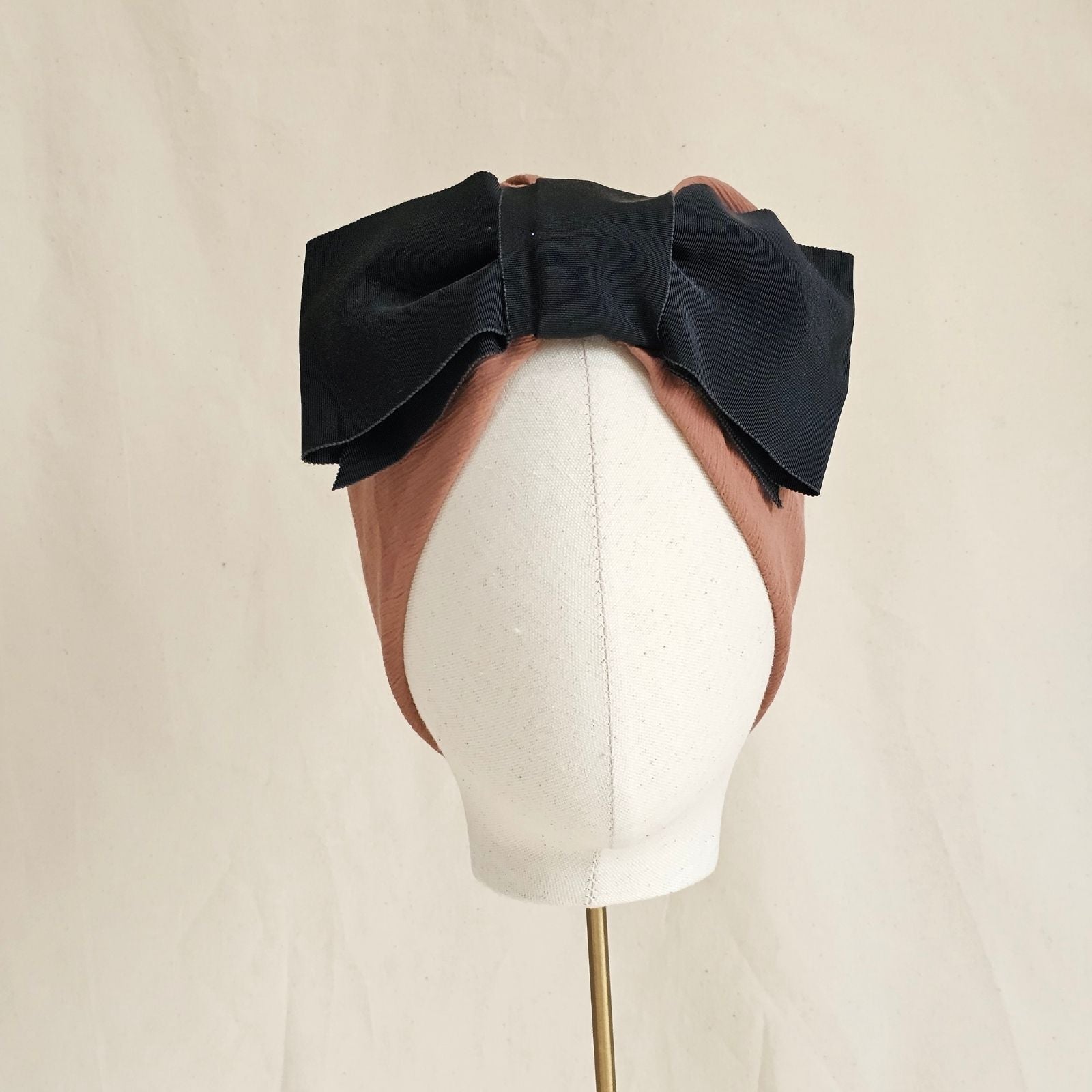 Tan cotton turban with dramatic black bow, front view.