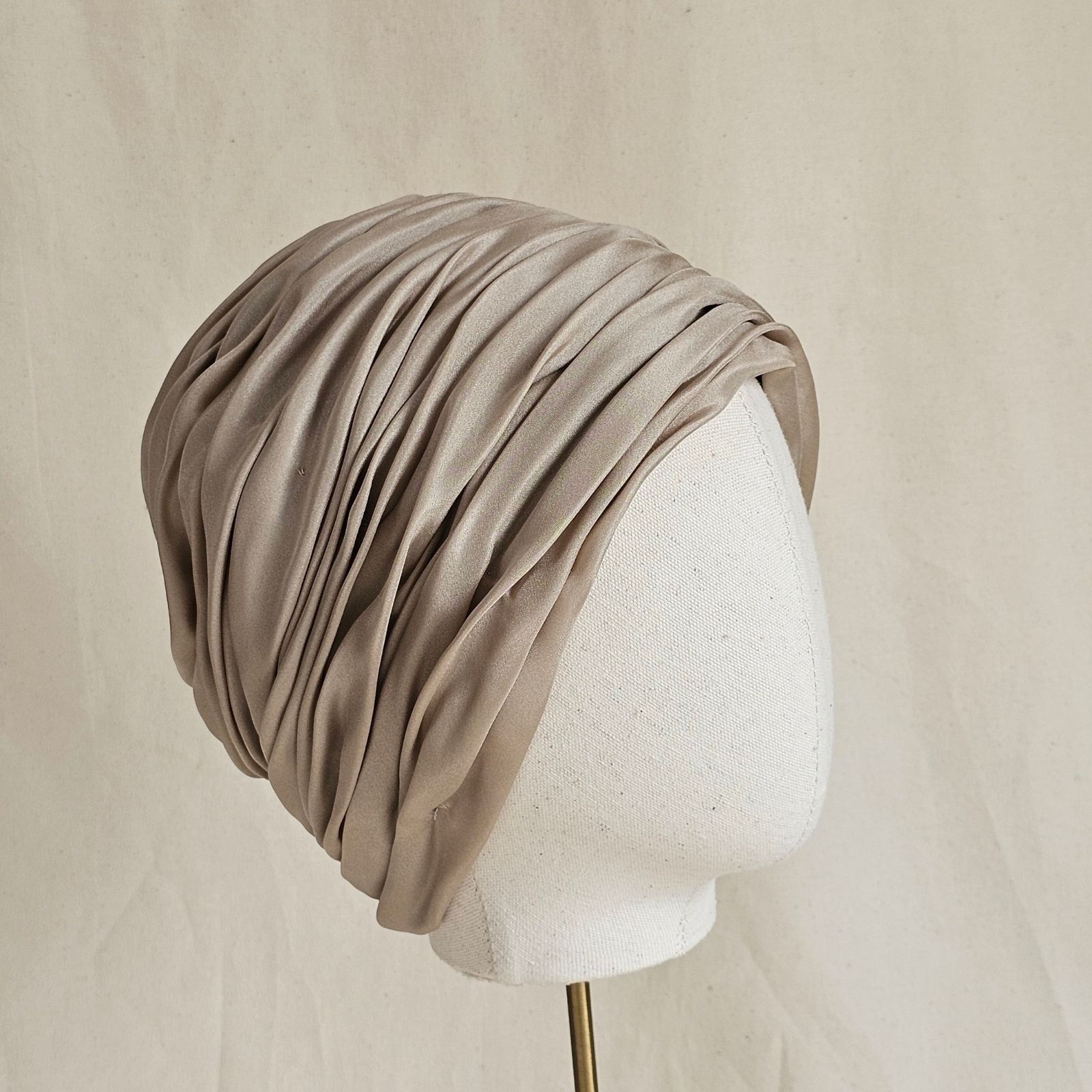 Taupe silk intricately gathered turban, side view.