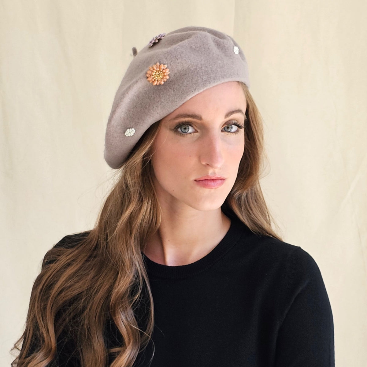 Taupe wool beret with flower and monogram embellishments,
worn on a model.