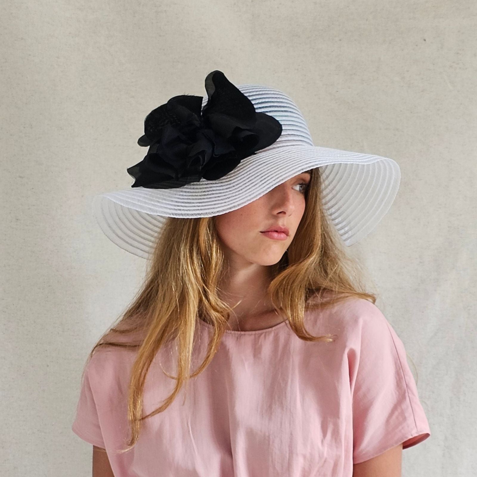 White crin floppy sunhat with dramatic black flower, angle view.