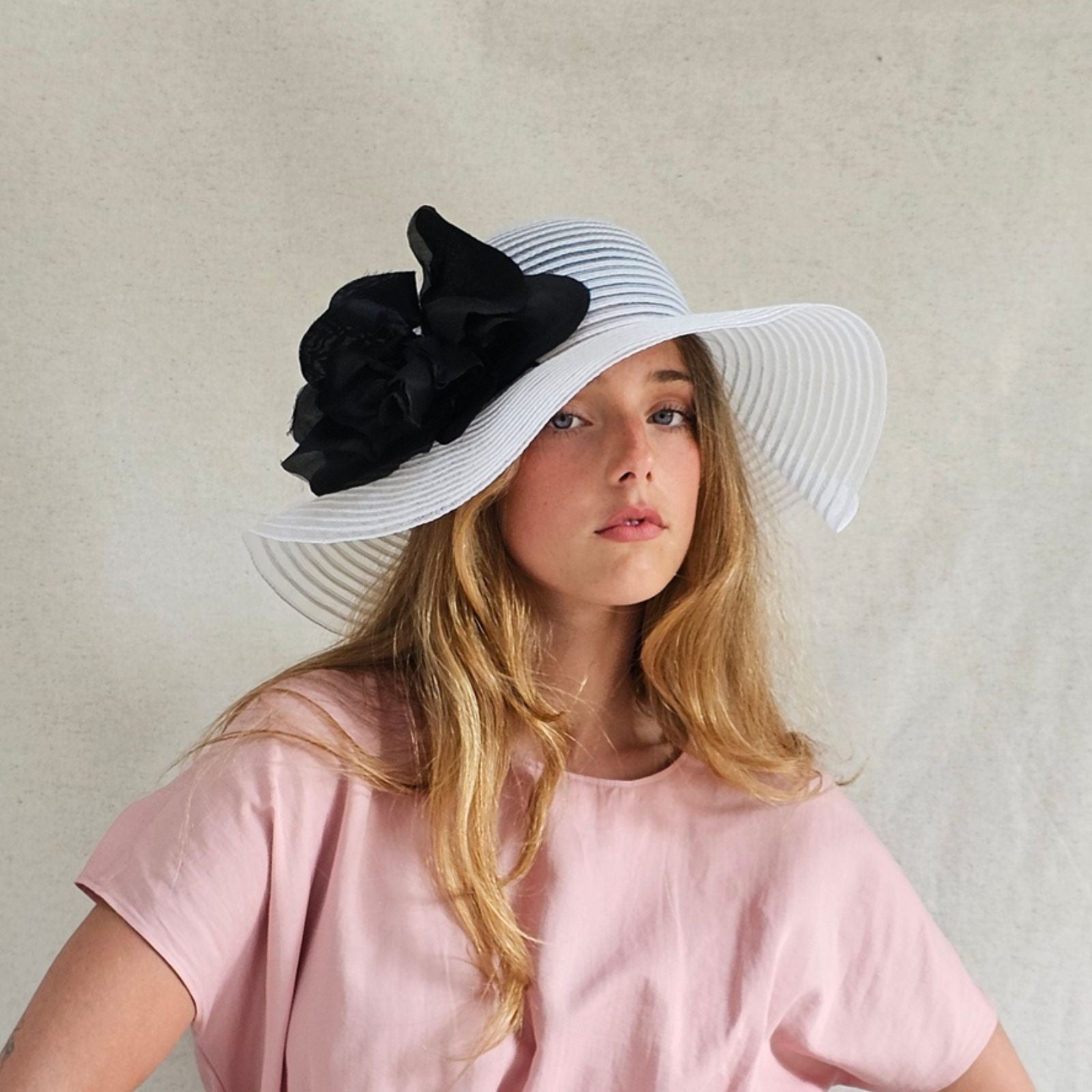 White crin floppy sunhat with dramatic black flower, front view.