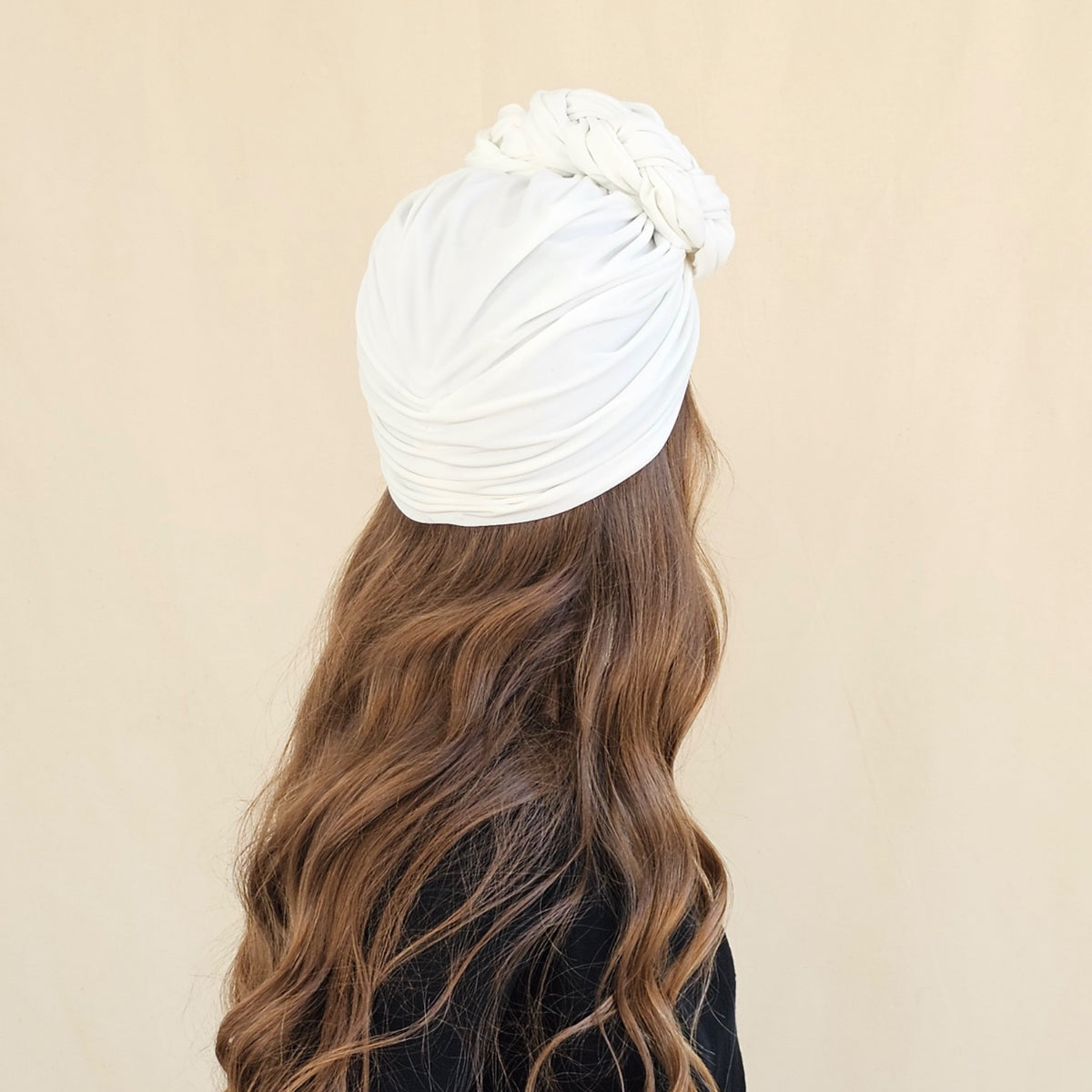 Back view of white jersey turban showing gathered fabric beneath
the braid rose.