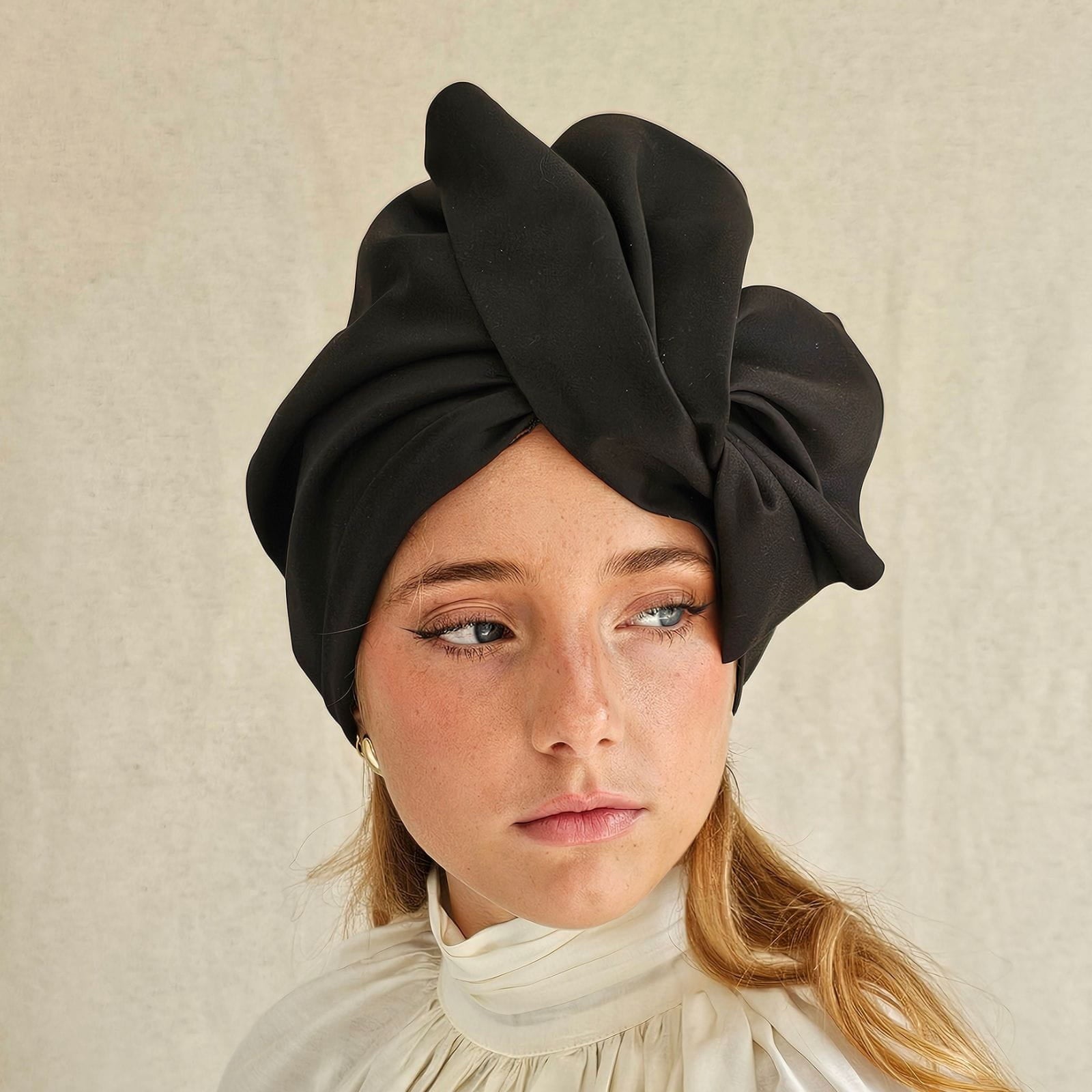 Black cotton turban with dramatic fold sculpting, front view.