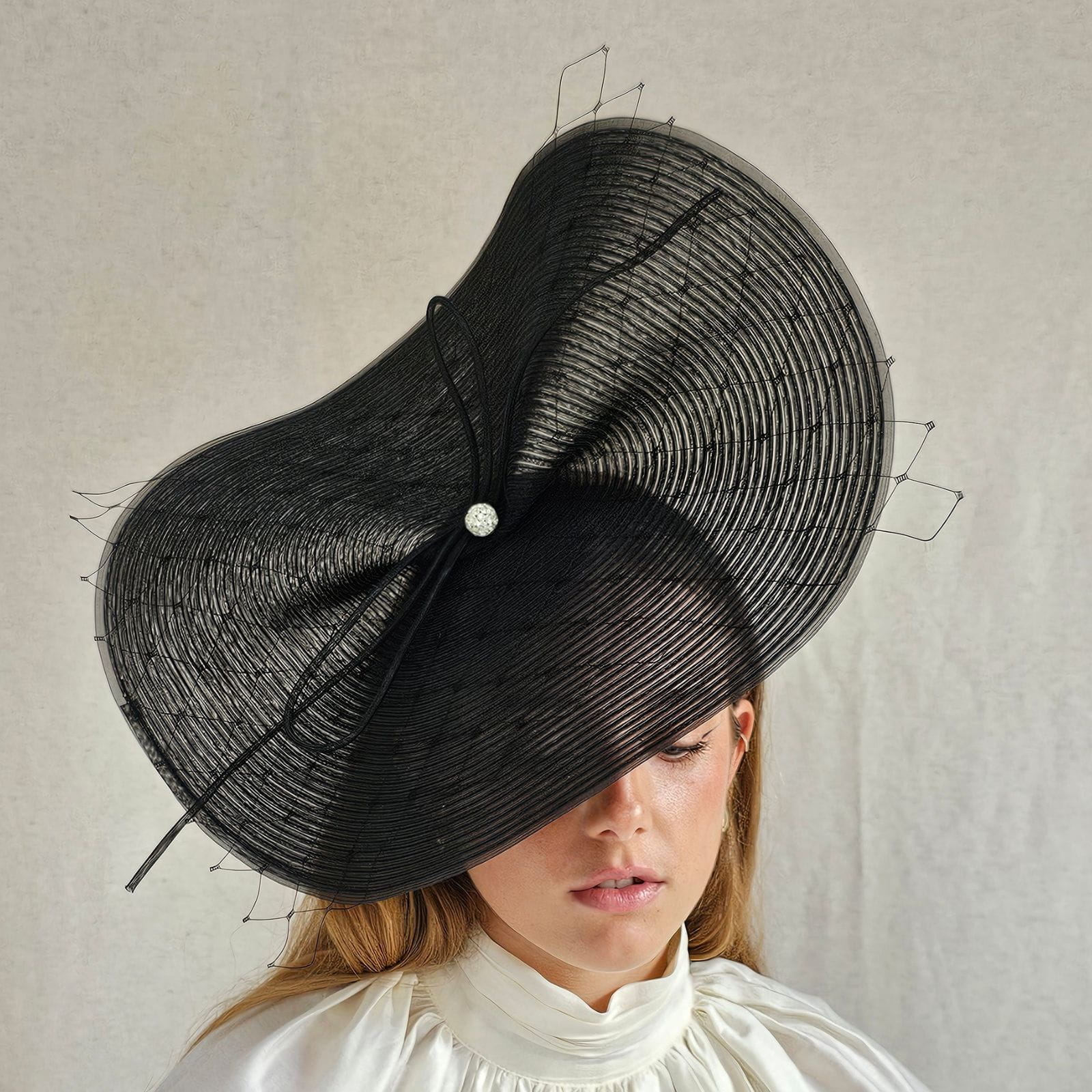 Black rin disc hat with subtle veiling and elegant bow with crystal diamanté globe centre, front view.