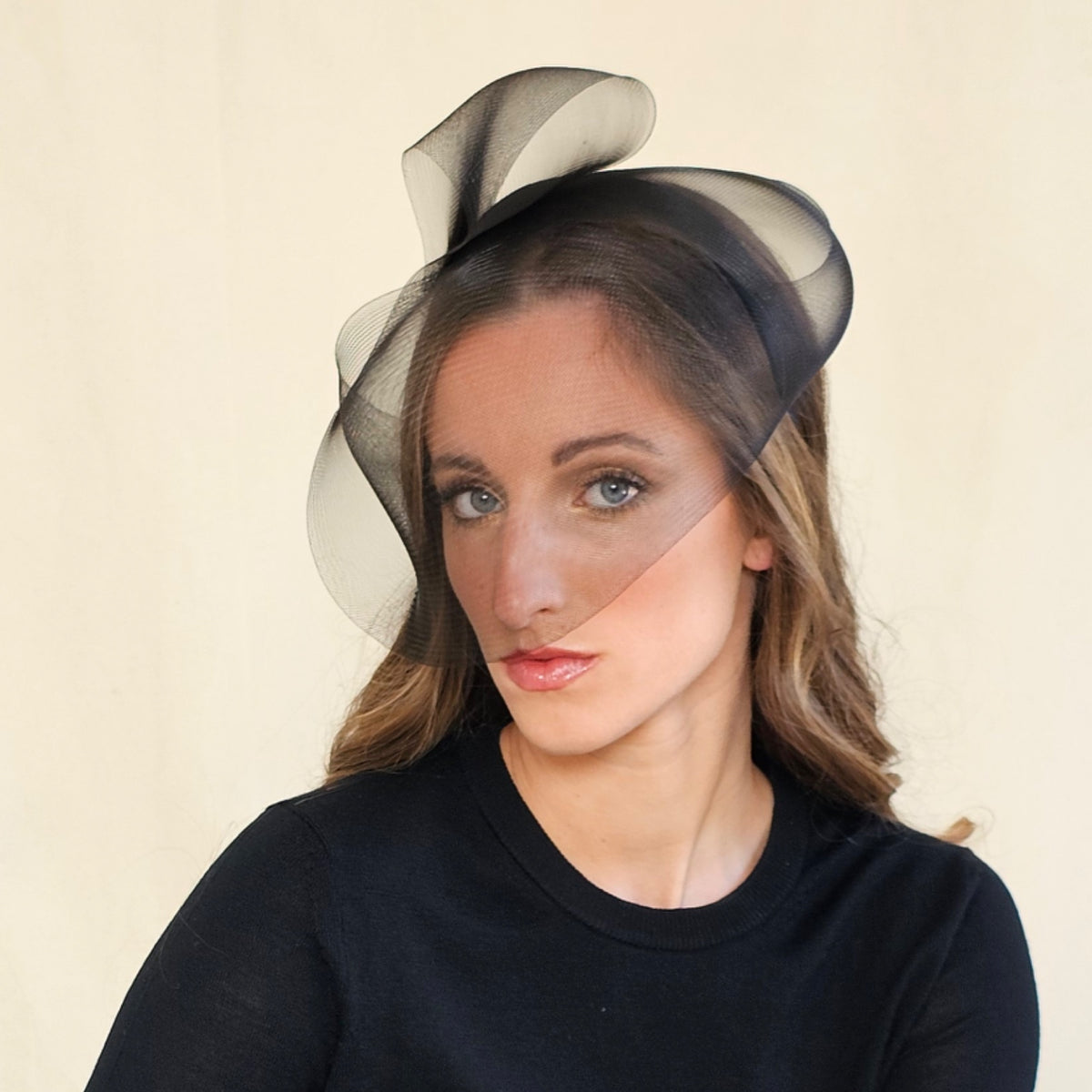 Black crin veil headband with sweeping loops above the crown,
angled view.