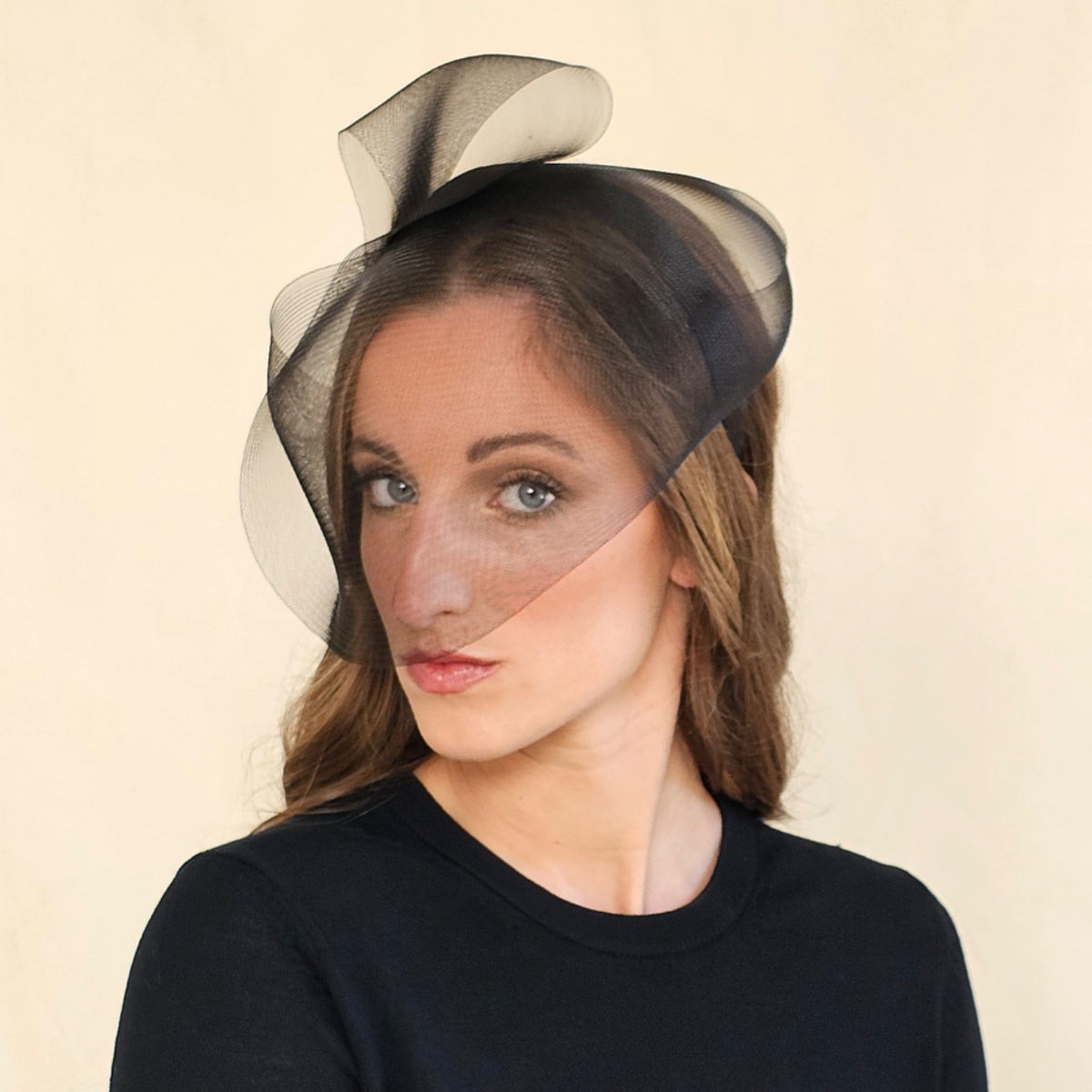 Model wearing black crin veil headband with sculptural loops
above the crown.