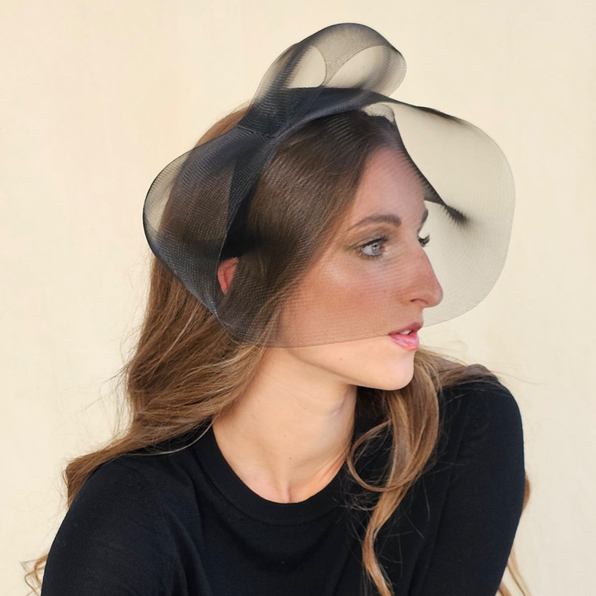 Side view of black crin veil headband on a model resting her chin
on her hand.