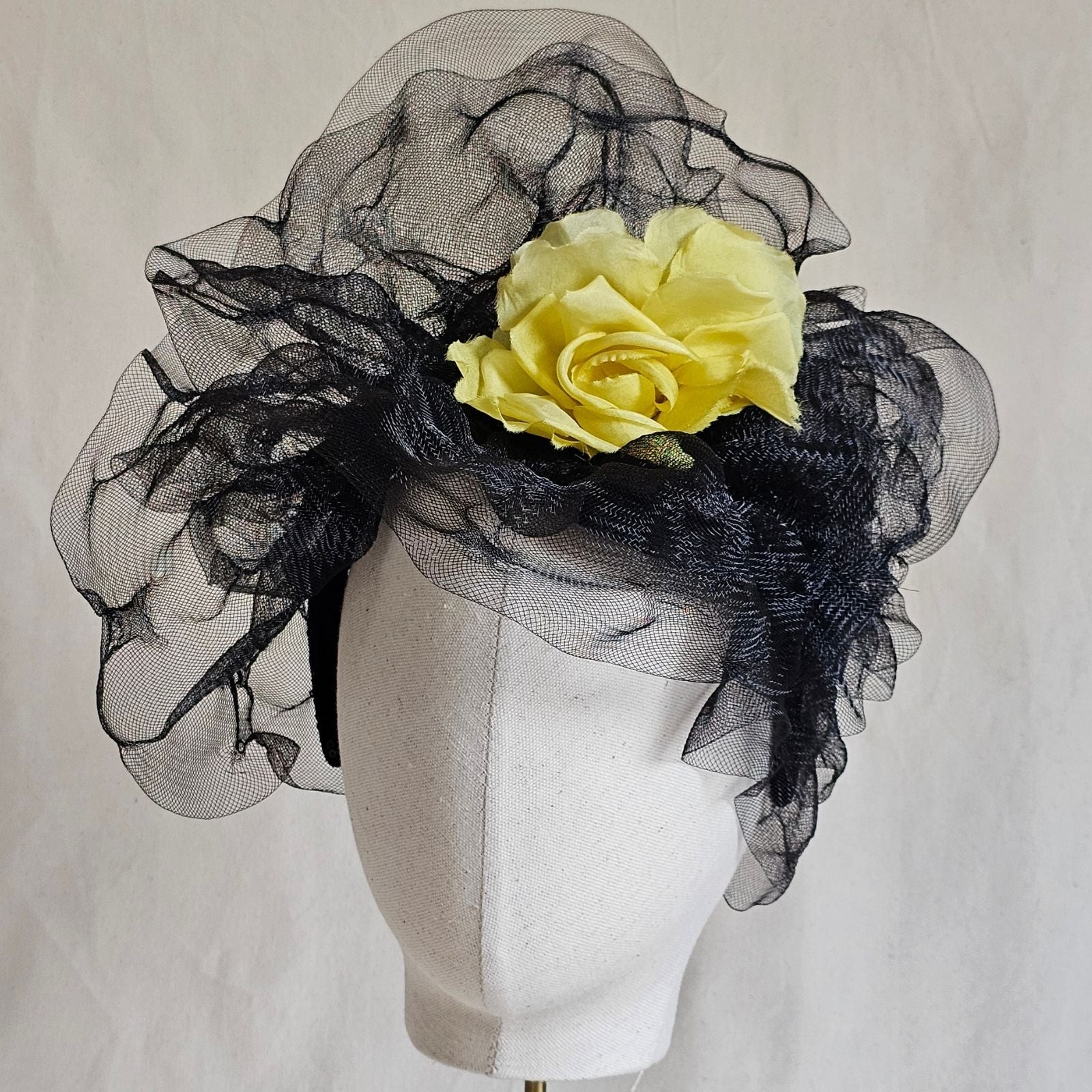 Black crin turban hat with striking yellow flower, front view.