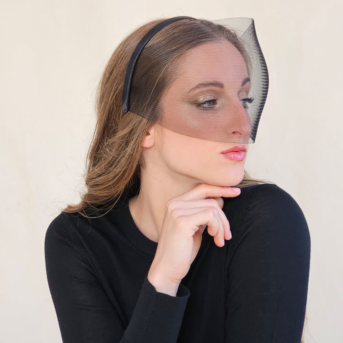 Side view of black crin face veil, model resting her chin on her
hand.