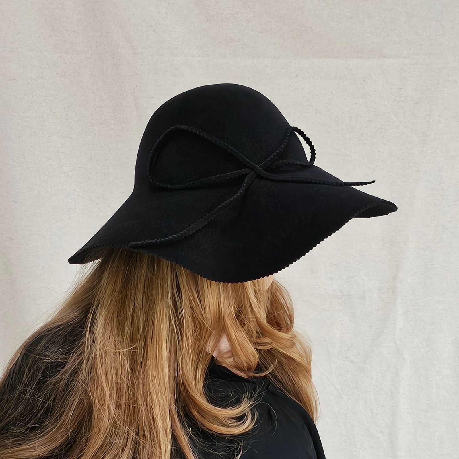 Black felt 1970s hat with elegant bow embellishment, right view.