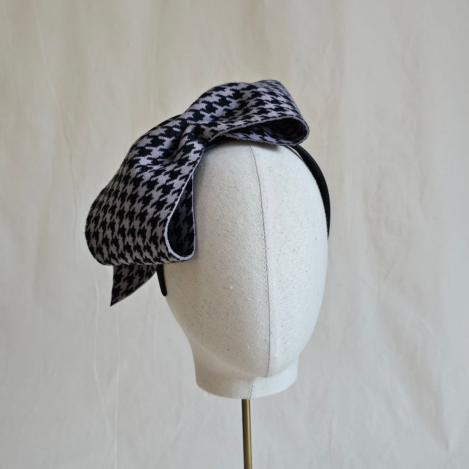 Headband with black grey houndstooth felt bow, front view.