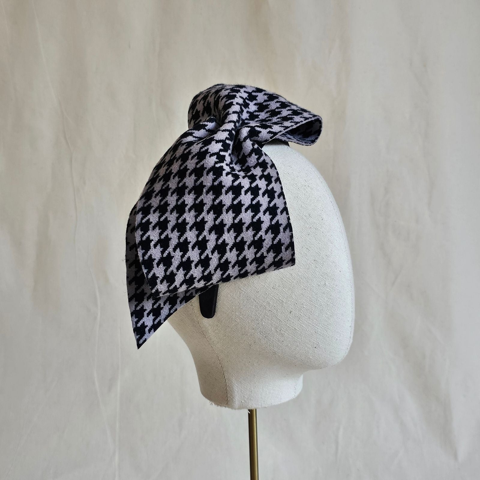 Headband with black grey houndstooth felt bow, side view.