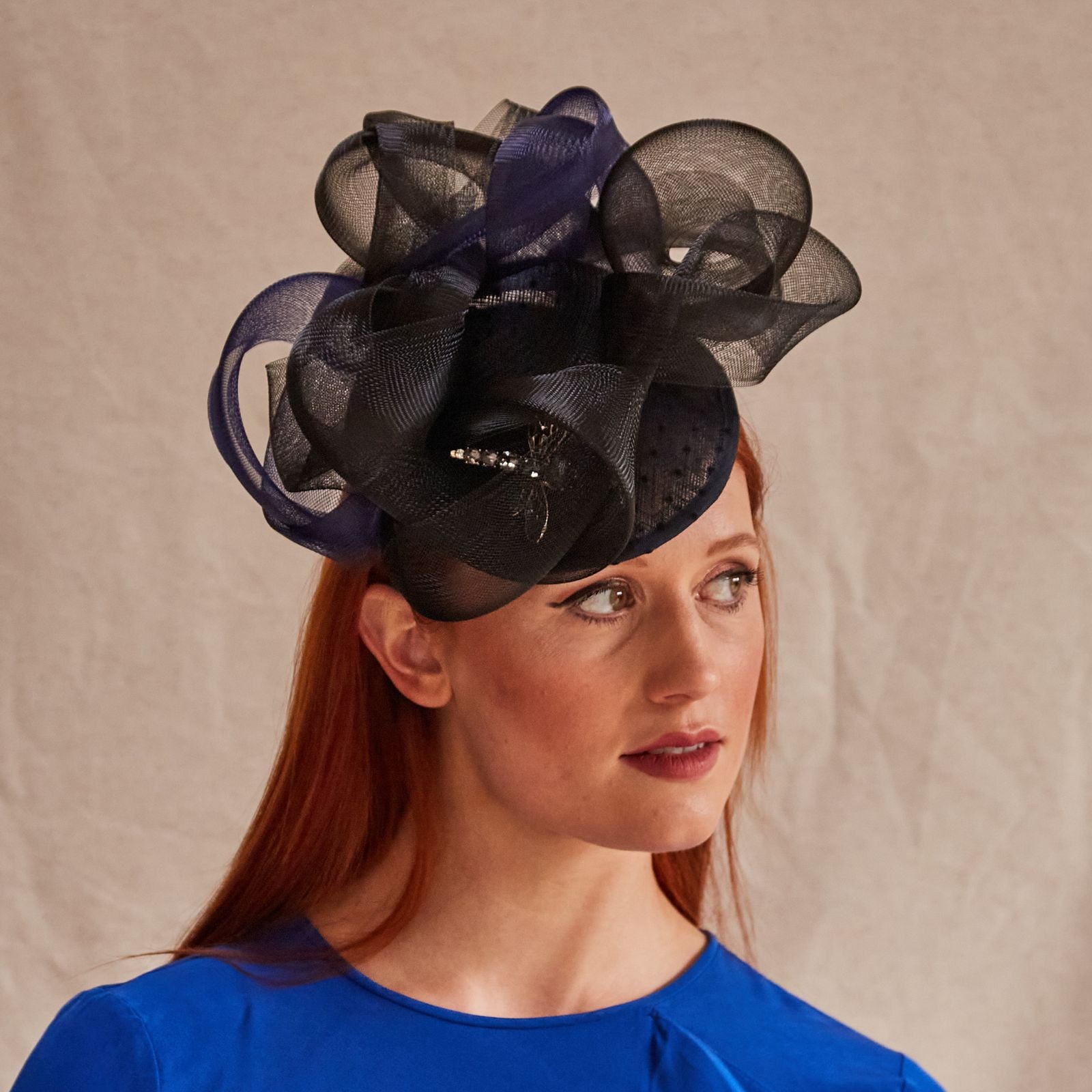 Black and navy peak fascinator with beautiful crin swirls and dragonfly embellishment, front view.