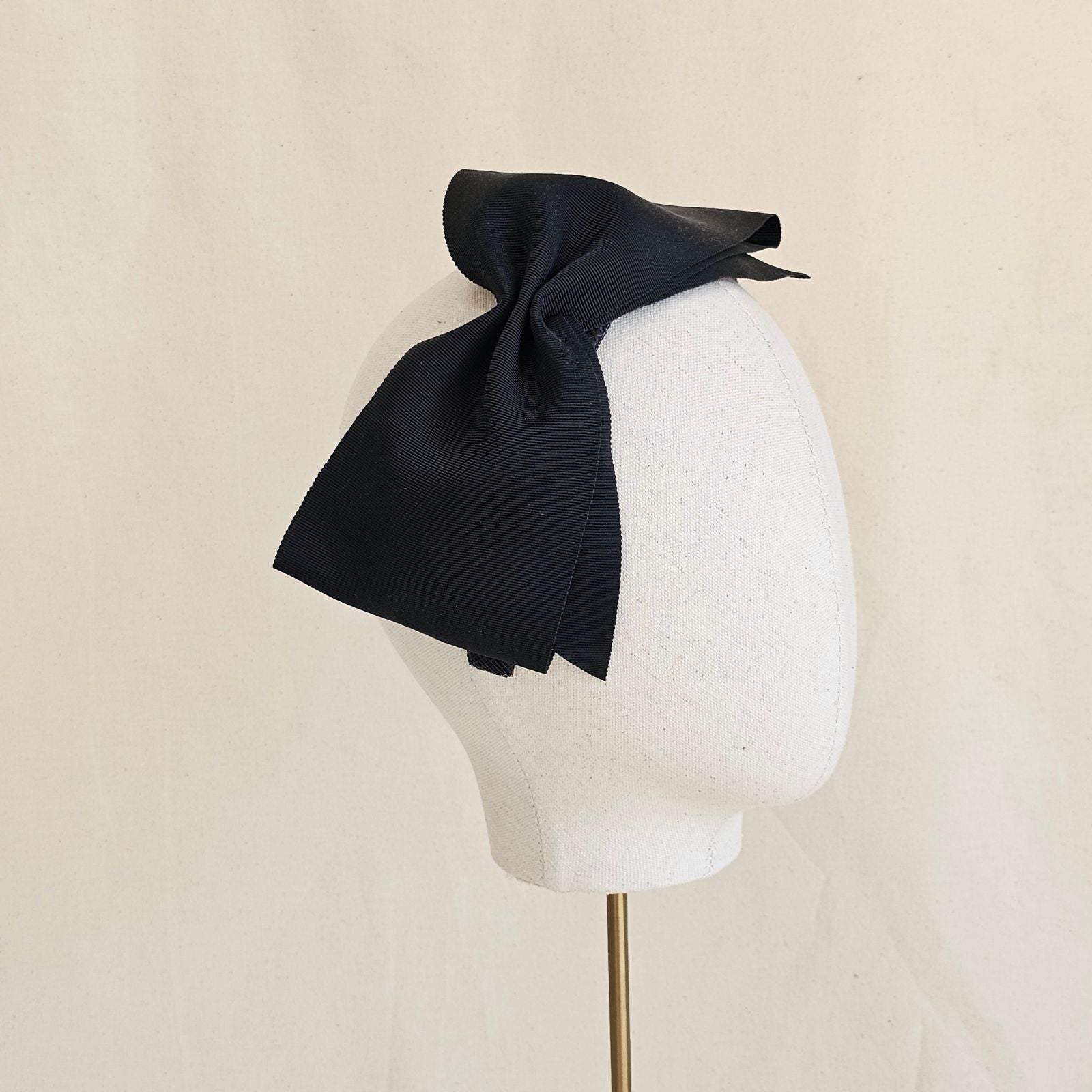 Black wide petersham bow on a headband, side view.
