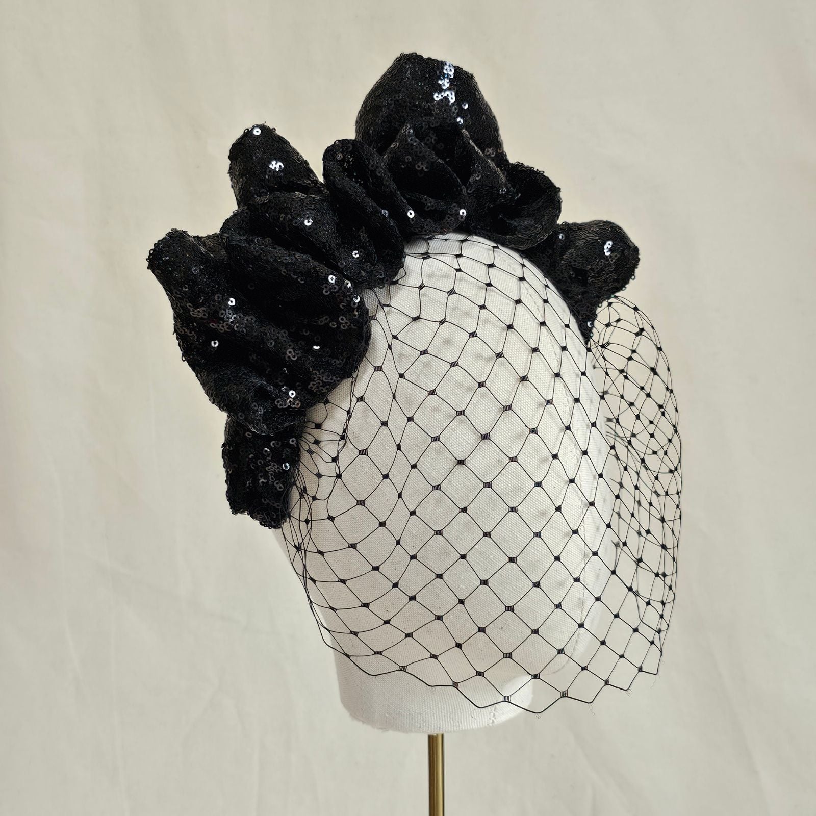 Black sequin gathered wave crown headband with birdcage face veil, angle view.