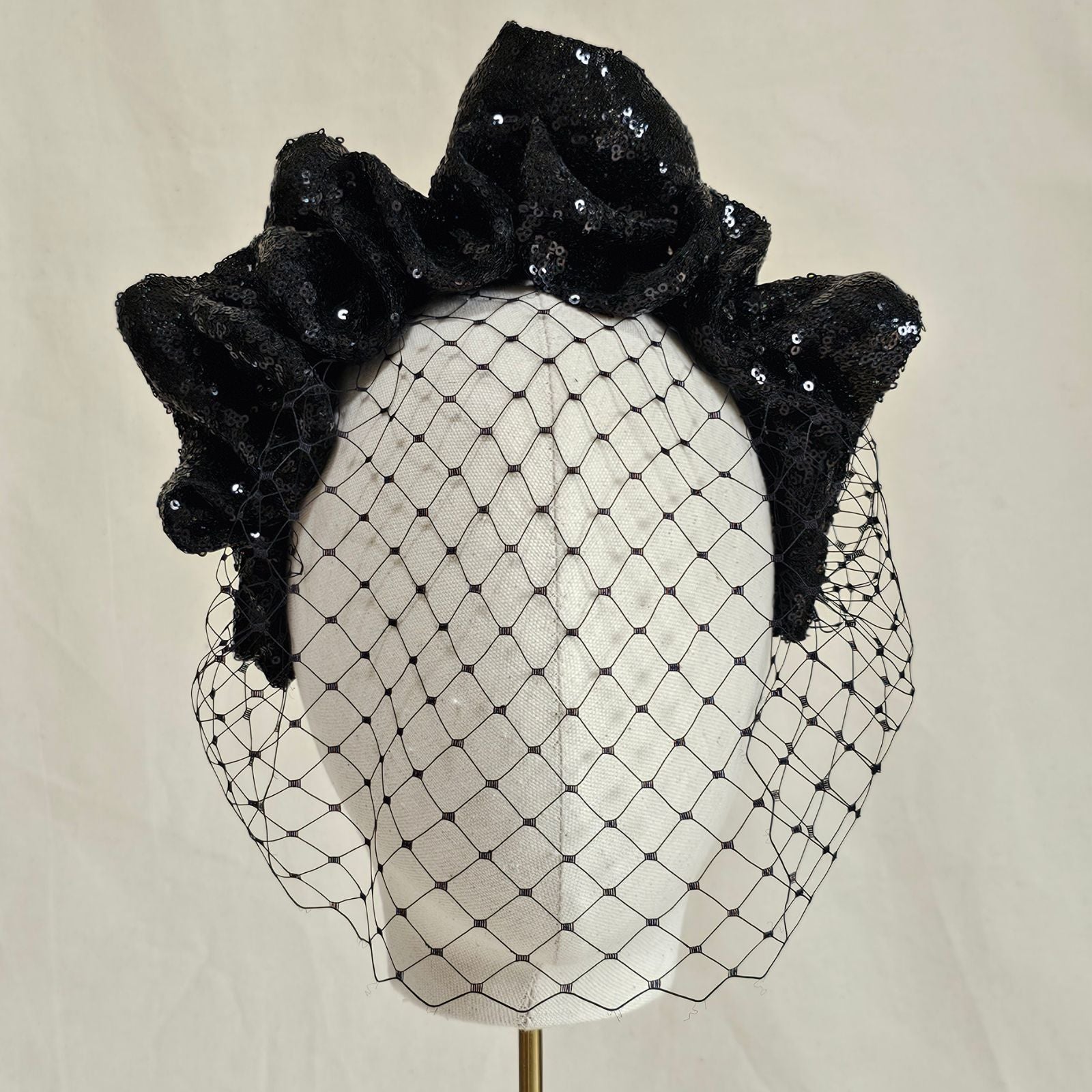 Black sequin gathered wave crown headband with birdcage face veil, front view.